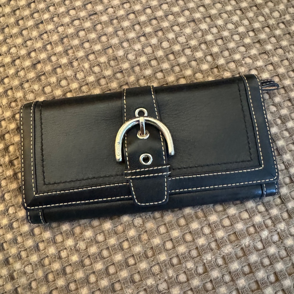 This is a Coach Signature Soho wallet in black leather with a buckle trifold